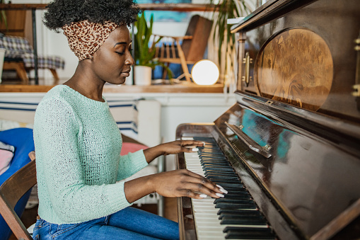 Young African American woman is playing piano at home