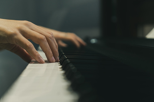 Picture of close-up woman hands playing a song on her piano