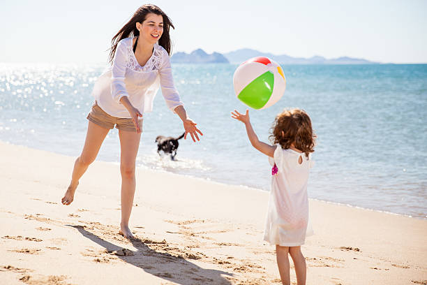Woman playing with a beach ball Happy young mother and her daughter playing with a beach ball on a sunny day beautiful young brunette girl playing with her dog stock pictures, royalty-free photos & images