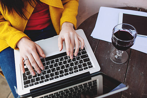 Woman playing with laptop in cafe with a glass of wine stock photo