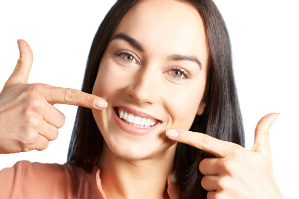 Woman Pointing To Her Smile With Perfect White Teeth stock photo