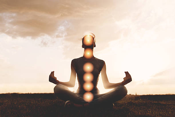 Woman practicing meditation in sunset, with chakras stock photo