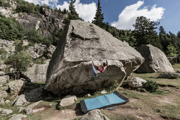 Woman practicing rock bouldering climbing Woman practicing rock bouldering climbing in the Pyrenees mountains bouldering stock pictures, royalty-free photos & images