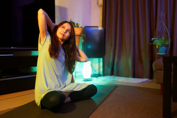 Woman practicing yoga at home at night stock photo