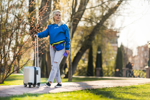 Woman walking with suitcase in the park