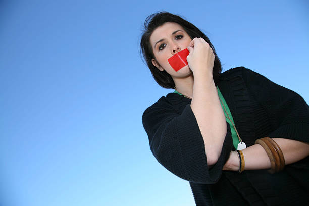 woman pulling tape off her mouth - plakband mond stockfoto's en -beelden