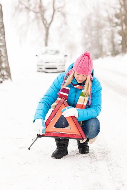 Woman put reflector triangle car breakdown winter stock photo