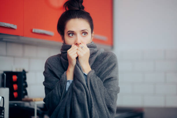 Woman Putting a Blanket on Suffering of Cold at Home stock photo