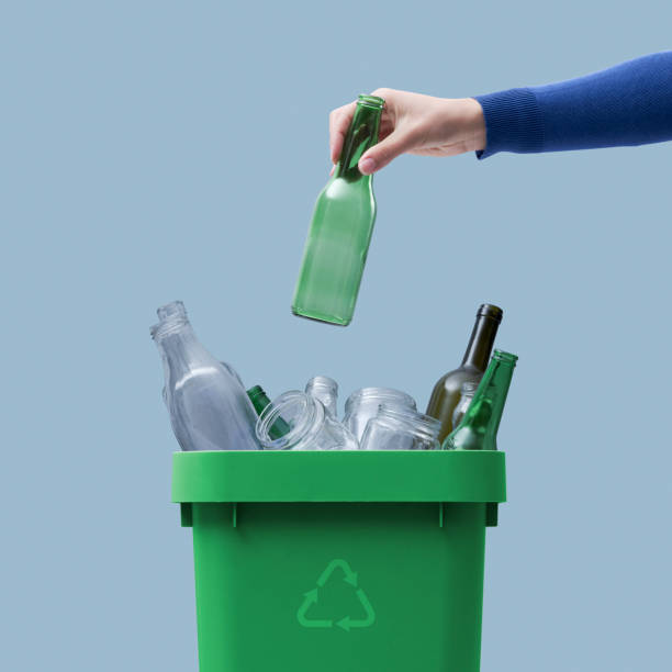Woman putting a glass bottle in the trash bin stock photo
