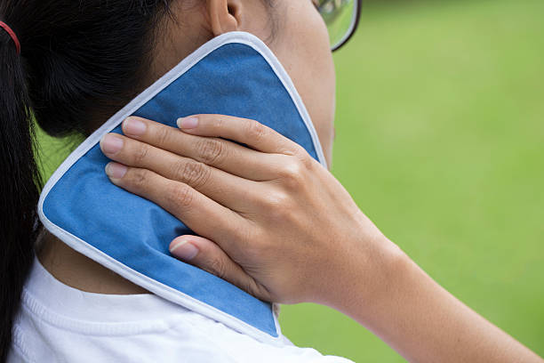 woman putting an ice pack on her neck pain stock photo