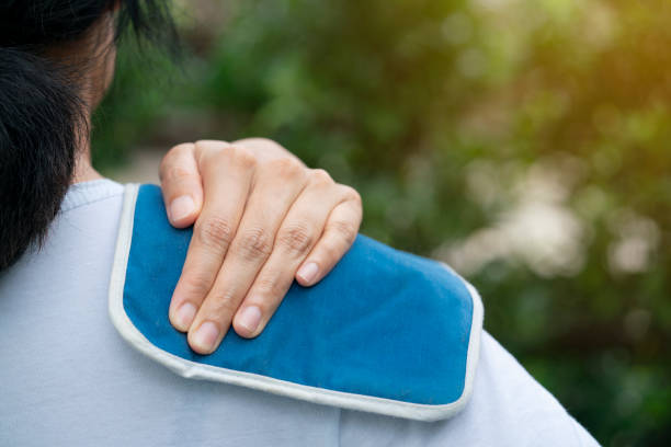 woman putting an ice pack on her shoulder pain stock photo