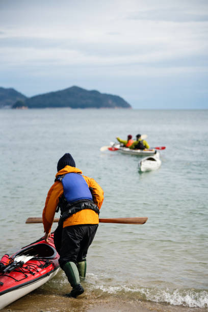 A woman putting her sea kayak in the water A woman putting her sea kayak in the water in prepartion japan  tourism stock pictures, royalty-free photos & images
