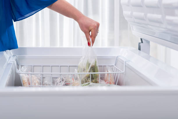 A woman putting some vegetables in the fridge stock photo