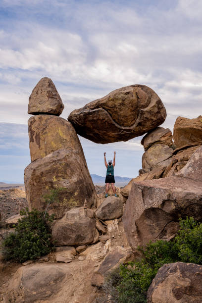 Woman Raises Arms Up Below Balanced Rock stock photo