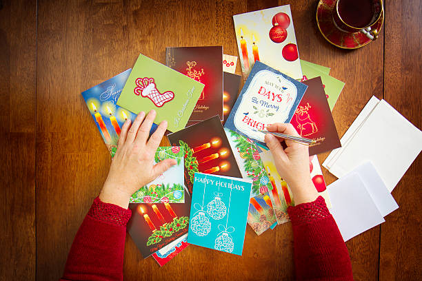 Woman Reaching For Holiday Cards On Table stock photo