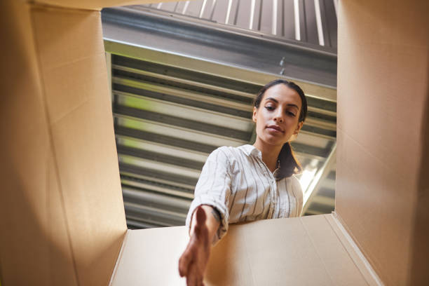 Woman Reaching into Box POV Low angle POV shot at young woman reaching into box while loading self storage unit, copy space self storage stock pictures, royalty-free photos & images