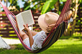 istock Woman reading book in hammock 1301556422