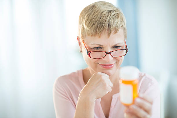 Woman Reading Label On Pill Bottle stock photo