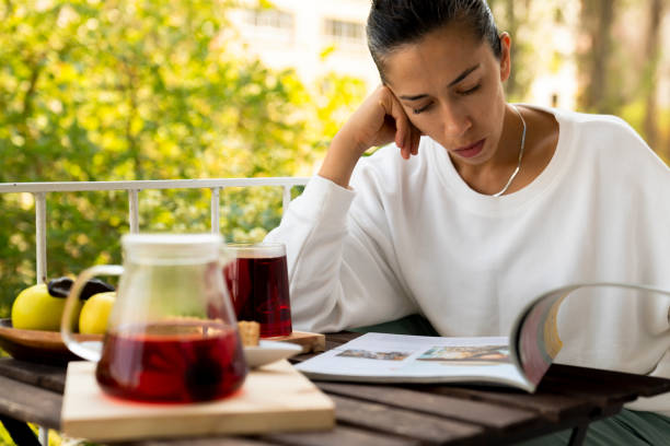 kvinna som läser tidning och dricka varma bryggt rött te. te för immunitet, ingredienser för behandling av förkylningar. - shodography bildbanksfoton och bilder