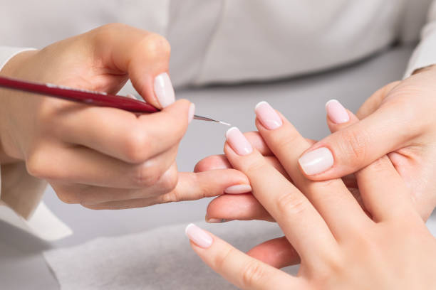 Woman receiving french manicure by beautician Hand of young woman receiving french manicure by beautician at nail salon. nail salon stock pictures, royalty-free photos & images