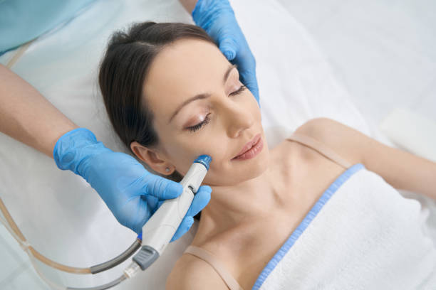 Woman receiving hydrafacial treatment in beauty salon stock photo