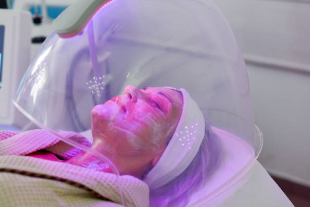 Woman receiving LED facial therapy for face. stock photo