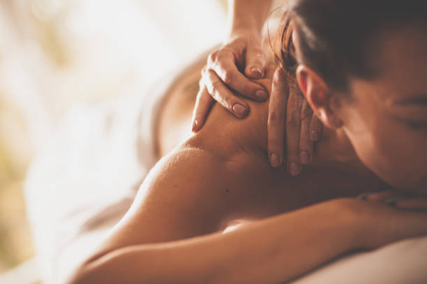 Woman receiving shoulder massage at spa Close-up shot of a woman enjoying relaxing back and shoulder massage at spa. spa treatment photos stock pictures, royalty-free photos & images