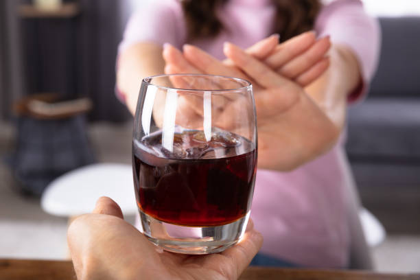 Woman Refusing Glass Of Drink Offered By Person Close-up Of A Woman's Hand Refusing Glass Of Drink Offered By Person avoidance stock pictures, royalty-free photos & images