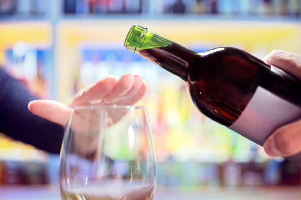 Woman rejecting more alcohol from wine bottle in bar Womans hand rejecting more alcohol from wine bottle in bar stop gesture stock pictures, royalty-free photos & images