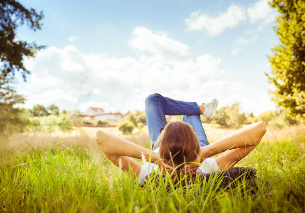 Woman relaxing on grass Young woman lying on grass looking up in the sky. lying down stock pictures, royalty-free photos & images