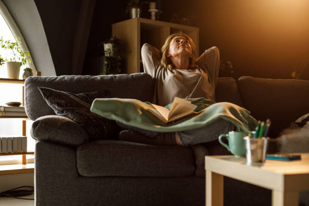 Woman relaxing on the sofa and contemplating after reading a book stock photo