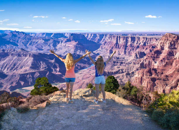 Woman relaxing on vacation trip in the mountains. Girls with raised hands relaxing on top of the mountain. Women with outstretched arms enjoying time together on hiking trip.Mother and daughter on vacation trip.South Rim. Grand Canyon National Park, Arizona, USA. south rim stock pictures, royalty-free photos & images