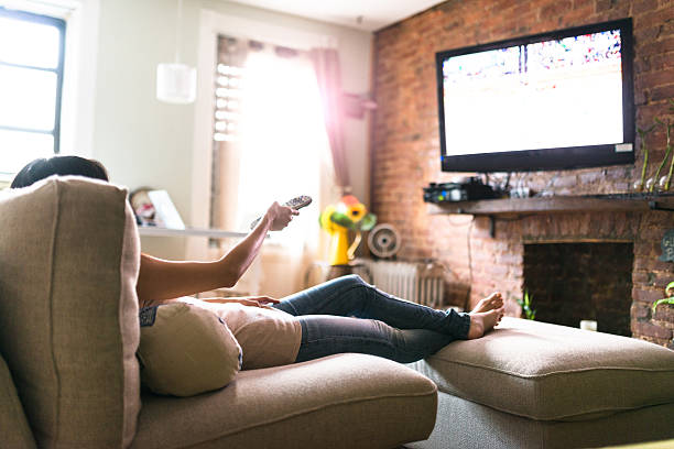 woman relaxing online on sofa reading some papers woman relaxing online on sofa reading some papers watching tv stock pictures, royalty-free photos & images