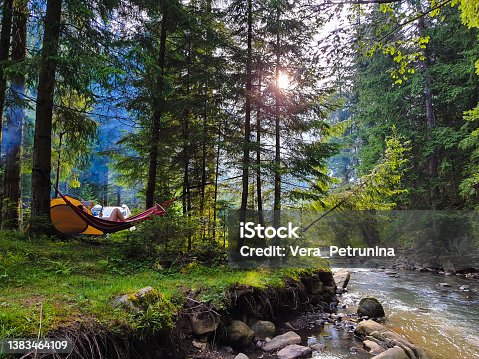 istock woman resting laying on hammock at camping site 1383464109