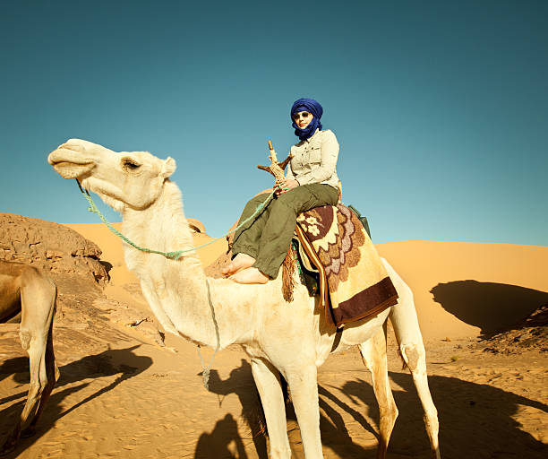 Woman riding a camel in Libyan Sahara desert Woman riding a camel in Libyan Sahara desert hot middle eastern girls stock pictures, royalty-free photos & images