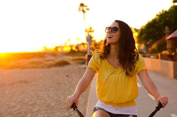 Woman riding bike laughing during the sunset stock photo