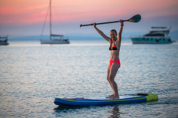 Woman riding SUP stand up paddle on vacation. stock photo