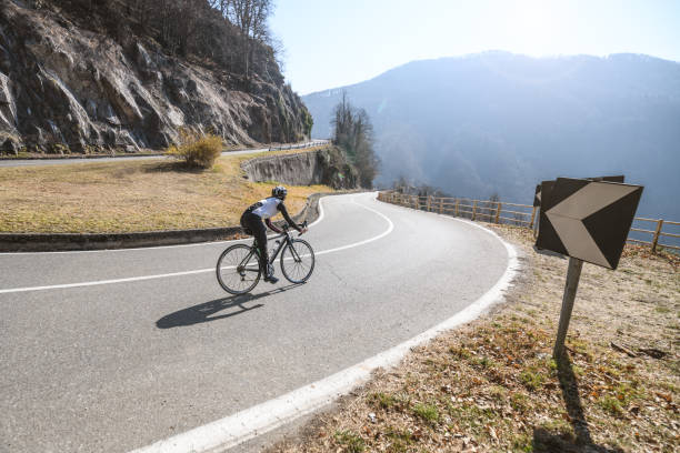Woman road cycling on Italian alpine road stock photo