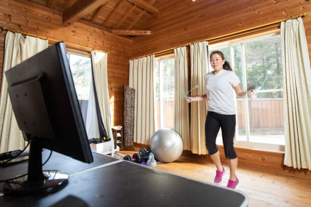 A woman rope-less skipping at home in front of pc screen stock photo