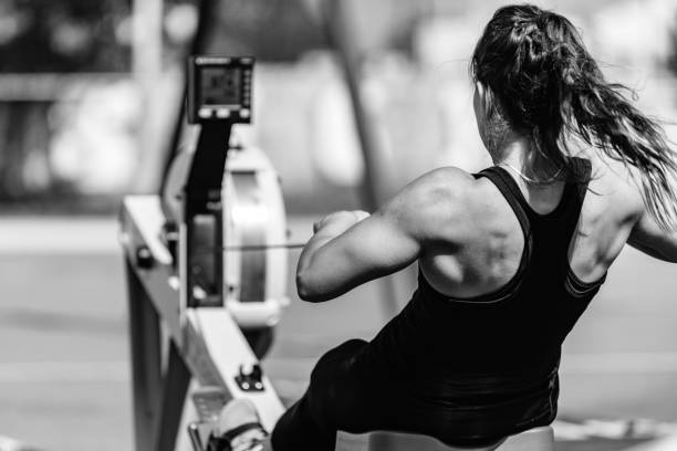 Woman, rowing machine, cross training, black and white Female athlete on rowing machine, black and white cross training stock pictures, royalty-free photos & images