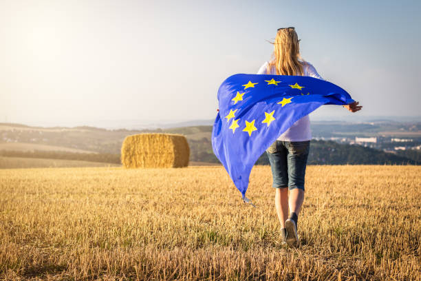 Woman running with waving european union flag in countryside. stock photo