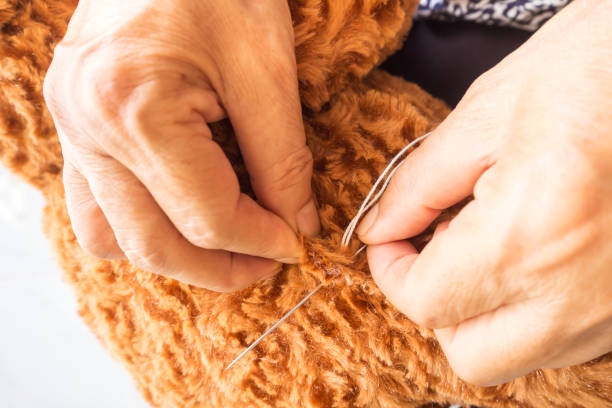 Woman sewing teddy bear, revamp a broken doll. Closeup on her hand used needle for patch a brown wool teddy bear. Woman sewing teddy bear, revamp a broken doll. Closeup on her hand used needle for patch a brown wool teddy bear. broken doll 1 stock pictures, royalty-free photos & images