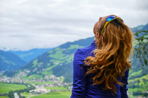 Woman shakes her brown, curly hair, during a hike above Zillertal valley, Austria. stock photo