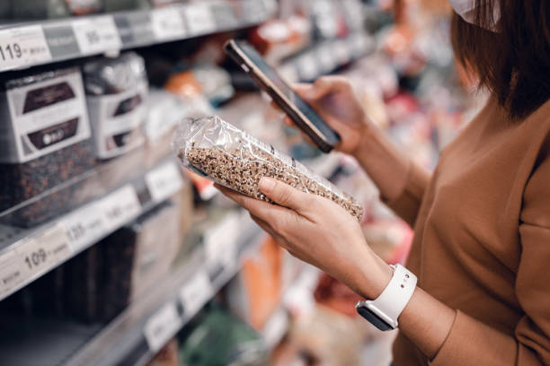 슈퍼마켓에서 쇼핑하고 제품 정보를 읽는 여성. 시장에서 음식을 구입 하는 의상. - 재료 뉴스 사진 이미지