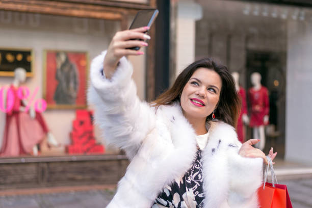 Woman shopping. Young woman taking selfie with her mobile phone. stock photo