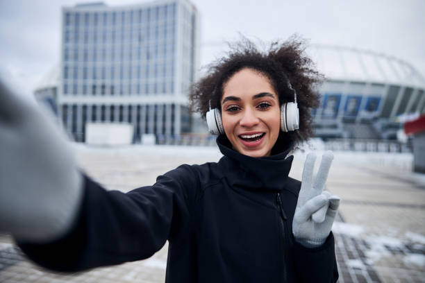 Woman showing a V sign while taking a photo Female raising the index and middle fingers on the left hand while smiling for a selfie dual citizenship stock pictures, royalty-free photos & images