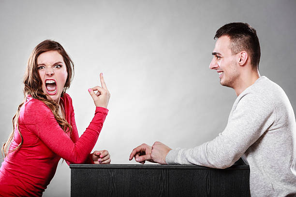 Woman showing middle finger gesture to man Crazy woman showing middle finger gesture to man. Insane girl gesturing in front of guy. Bad date dating. bad date stock pictures, royalty-free photos & images