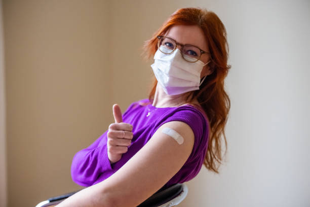 Woman showing thumbs up after getting covid-19 vaccine stock photo