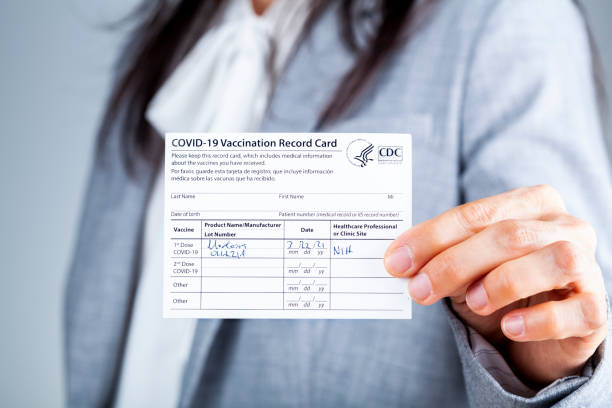 woman showing Vaccination record card Clarksburg, MD, USA 03-29-2021: A caucasian businesswoman is showing her CDC issued COVID vaccination record card as a proof of immunization. It has the date and lot number on it. cdc vaccine card stock pictures, royalty-free photos & images