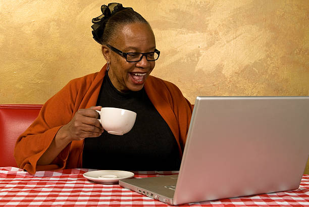 A woman sipping a cup of coffee in an Internet cafe stock photo